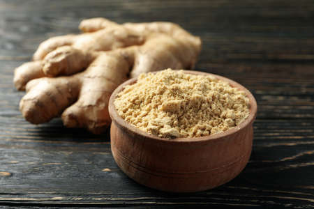 Ginger and bowl with ginger powder on wooden backgroundの写真素材