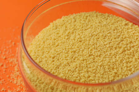 Glass jar with couscous on orange backgroundの写真素材