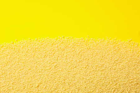 Raw couscous on yellow background, space for textの写真素材