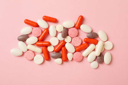 Different pills on pink background, top view