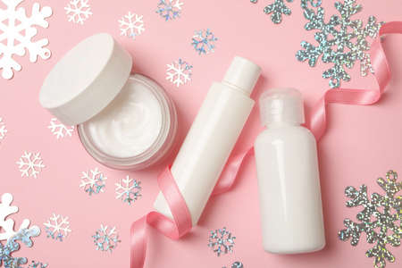 Cosmetics and snowflakes on pink background, top view