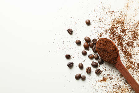 Spoon with ground coffee and beans on white background