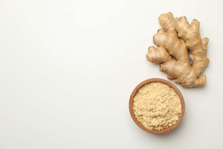 Ginger and bowl with ginger powder on white background