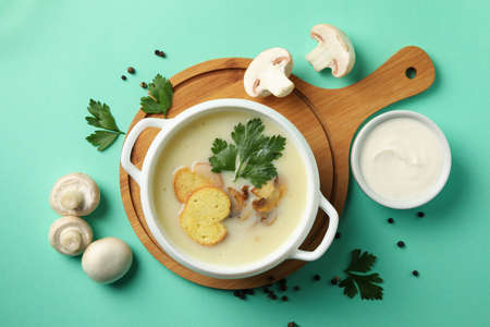 Concept of tasty lunch with bowl of mushroom soup on mint backgroundの写真素材