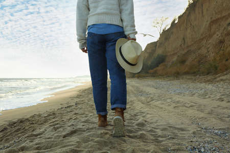 Handsome woman hold hat on sandy beachの写真素材