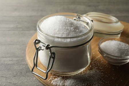 Board with glass jar of salt on gray table