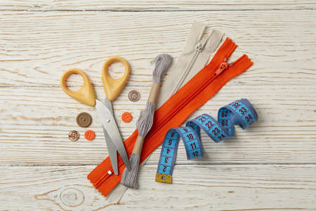 Sewing supplies on white wooden background, top view