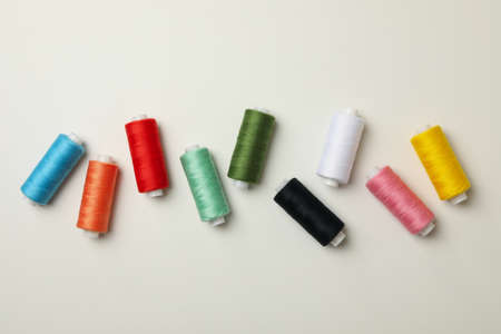 Color sewing threads on white background, top view
