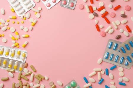 Circle made of pills on pink background, space for text