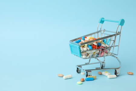 Shop cart with different pills on blue background