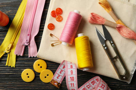 Sewing supplies on wooden background, top view