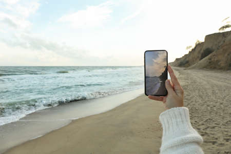 Female hand hold phone with making selfie on sea