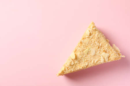Piece of delicious Napoleon cake on pink background