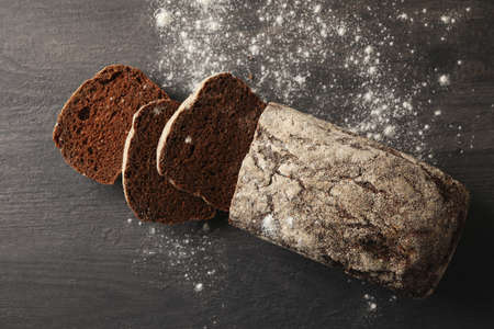 Fresh baked rye bread and flour on black background