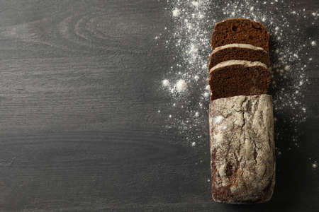 Fresh baked rye bread and flour on black background