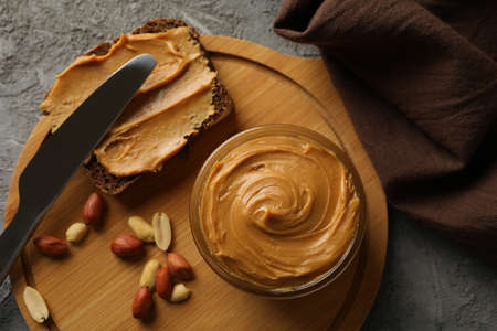 Concept of tasty breakfast with peanut and peanut butter on gray table