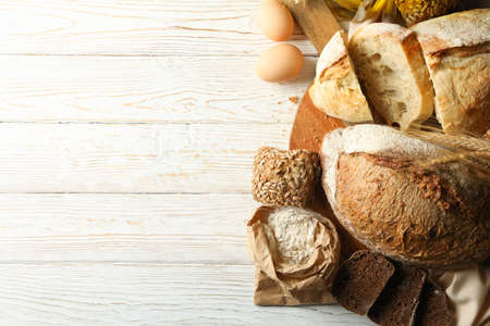 Concept of bakery products with fresh bread on white wooden background