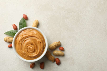 Peanut and leaves, and bowl with peanut butter on white background