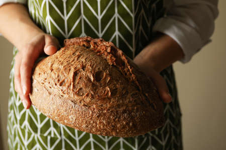 Woman in apron hold fresh baked bread
