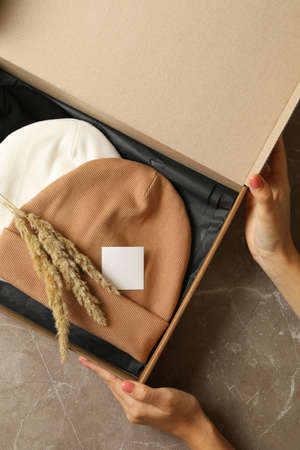 Female hands hold box with different beanies on gray tableの写真素材