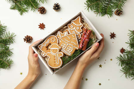 Female hands hold box with Christmas cookie on white background