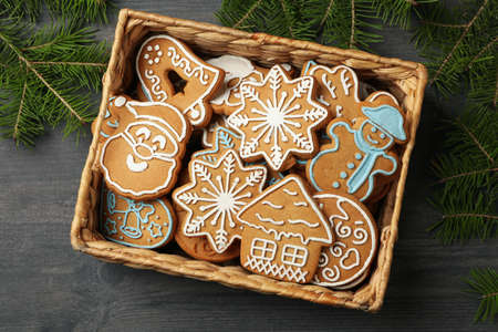 Basket with Christmas cookies and pine branches on dark table