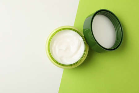 Jar of cosmetic cream and leaves on two tone backgroundの写真素材