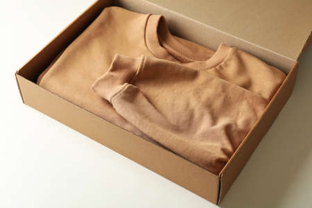 Box with sweatshirt on white background, space for textの写真素材