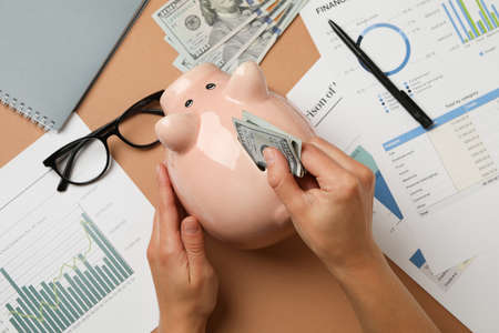 Concept of financial planning with woman puts money in piggy bank