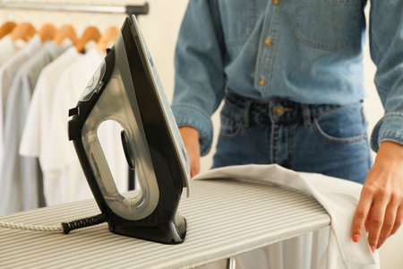 Woman in jeans ironing shirt with ironの写真素材