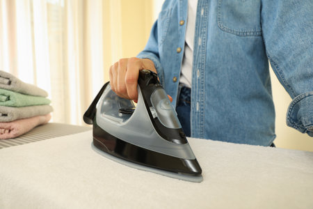 Woman in jeans ironing towel on ironing boardの写真素材