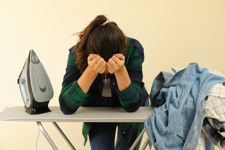 Tired woman bent over an ironing boardの写真素材
