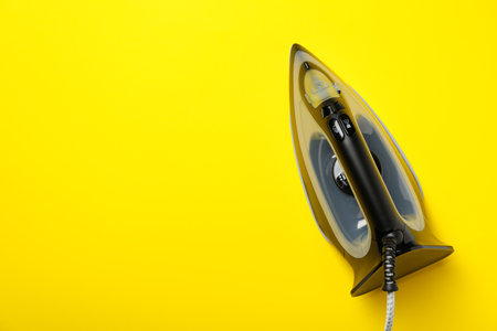 Modern iron on yellow background, space for textの写真素材