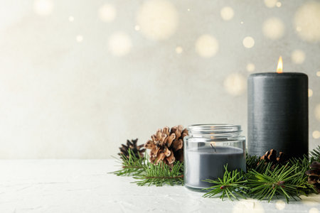 Scented candles and pine branches with cones on white tableの写真素材