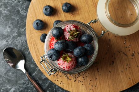 Board with jar of delicious chia pudding on black smokey tableの写真素材