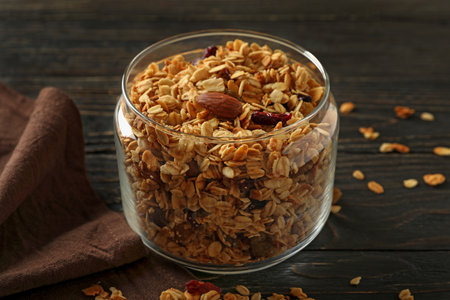 Glass jar with tasty granola on wooden backgroundの写真素材