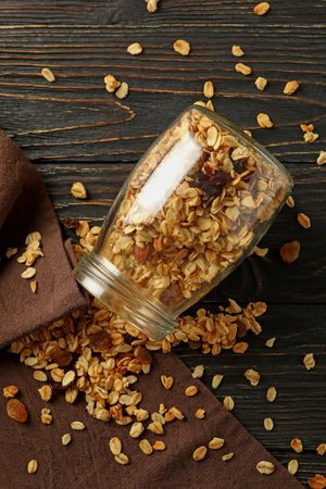 Glass jar with tasty granola on wooden backgroundの写真素材