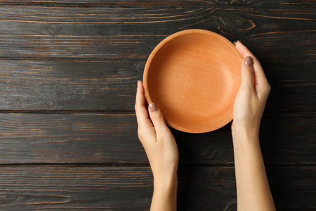 Female hands holding bowl on wooden backgroundの写真素材