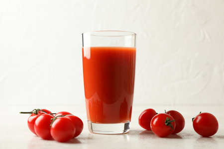 Glass of tomato juice and tomatoes on white textured backgroundの写真素材