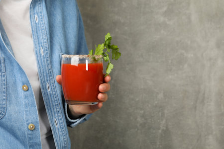 Woman hold glass of tomato juice on gray backgroundの写真素材