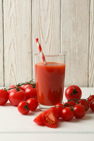 Glass with tomato juice and straw and tomatoes on wooden backgroundの写真素材