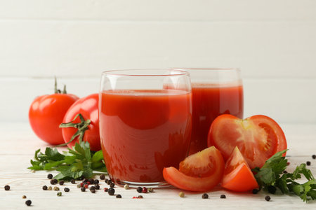 Glasses with tomato juice, tomatoes and spices on wooden backgroundの写真素材