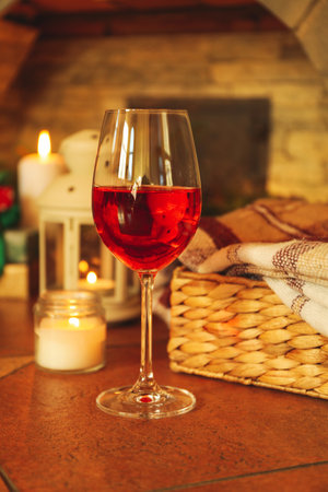 Glass of red wine and Christmas accessories against fireplaceの写真素材