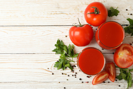 Glasses with tomato juice, tomatoes and spices on wooden backgroundの写真素材
