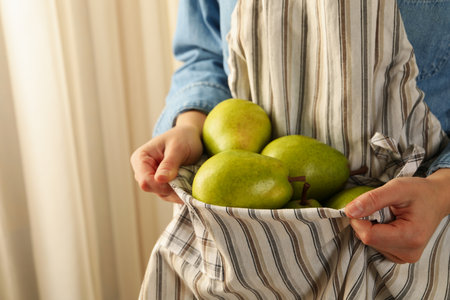 Woman holding fresh green pears in apronの写真素材