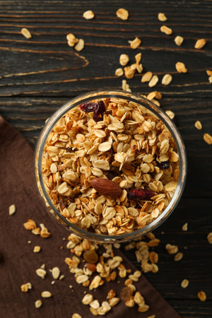Glass jar with tasty granola on wooden background