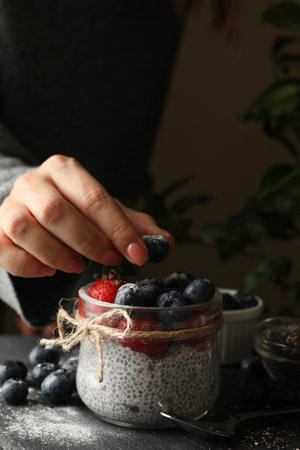 Woman puts blueberry in jar with chia puddingの写真素材