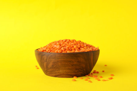 Bowl with red legumes on yellow background, space for textの写真素材