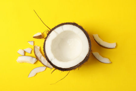 Half of fresh coconut on yellow background