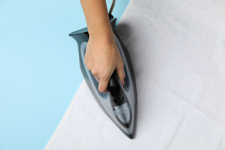 Female hand hold iron on white towelの写真素材